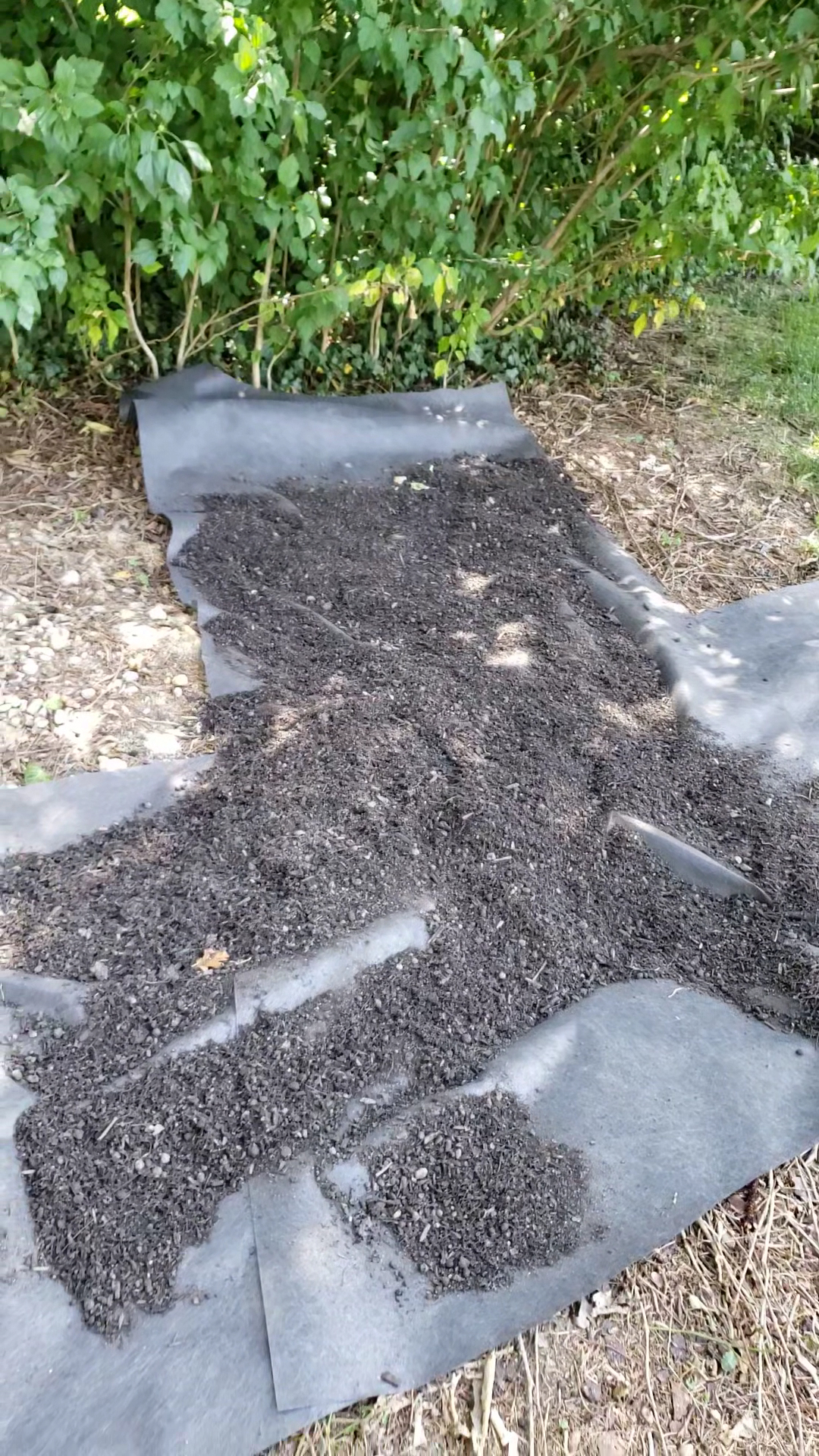 Landscape fabric and fresh mulch being installed in a garden bed